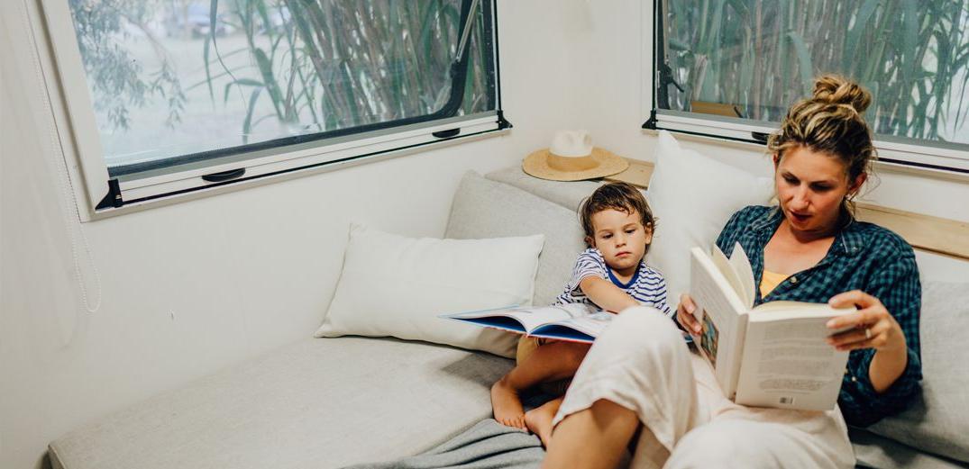 A mom and her son reading in their RV.